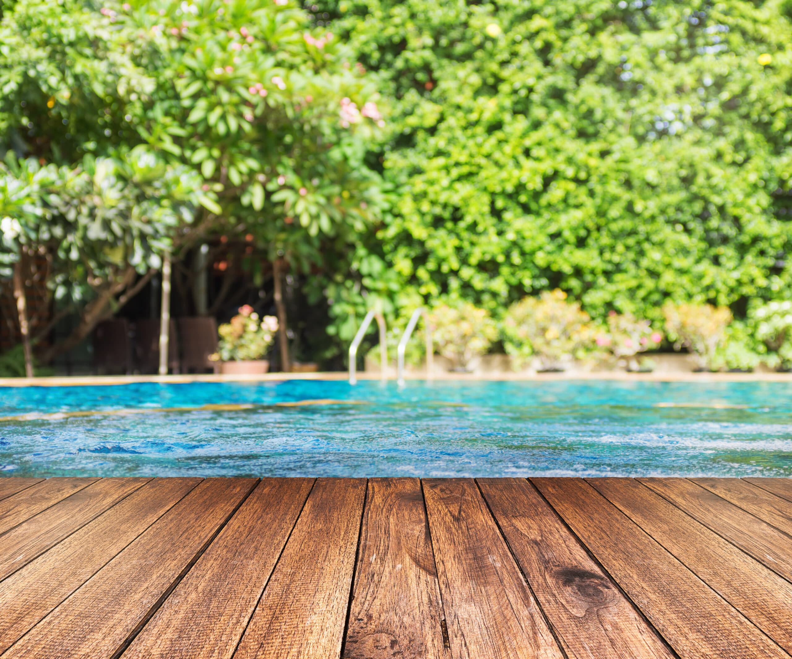 Zwembad met houten terras omringd door groen